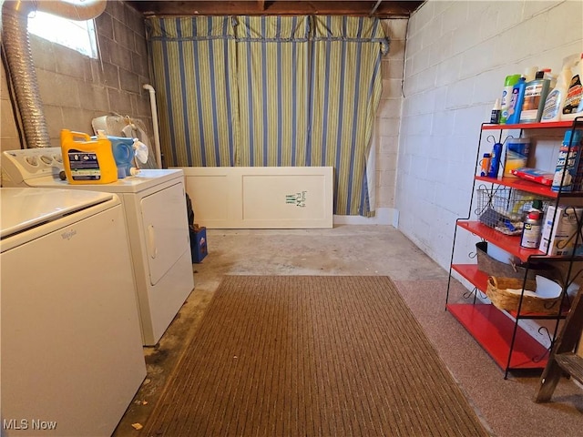 clothes washing area featuring concrete block wall, laundry area, and washer and dryer