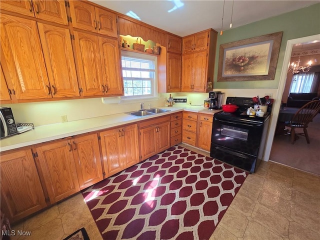 kitchen featuring brown cabinetry, an inviting chandelier, light countertops, black range with electric cooktop, and a sink