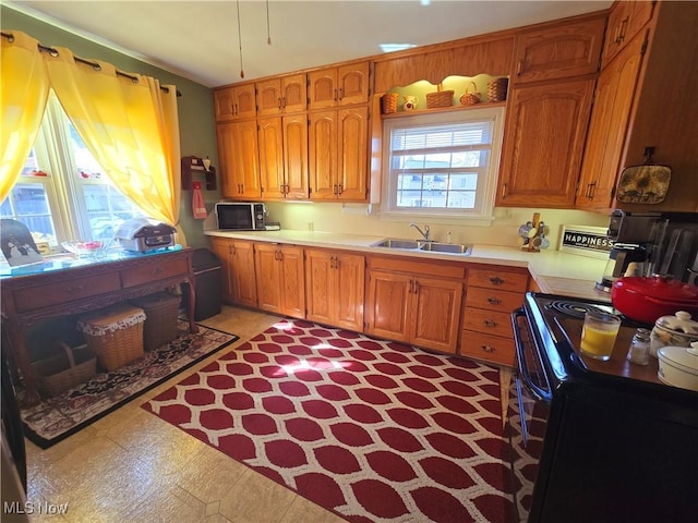 kitchen with brown cabinetry, black / electric stove, light countertops, and a sink