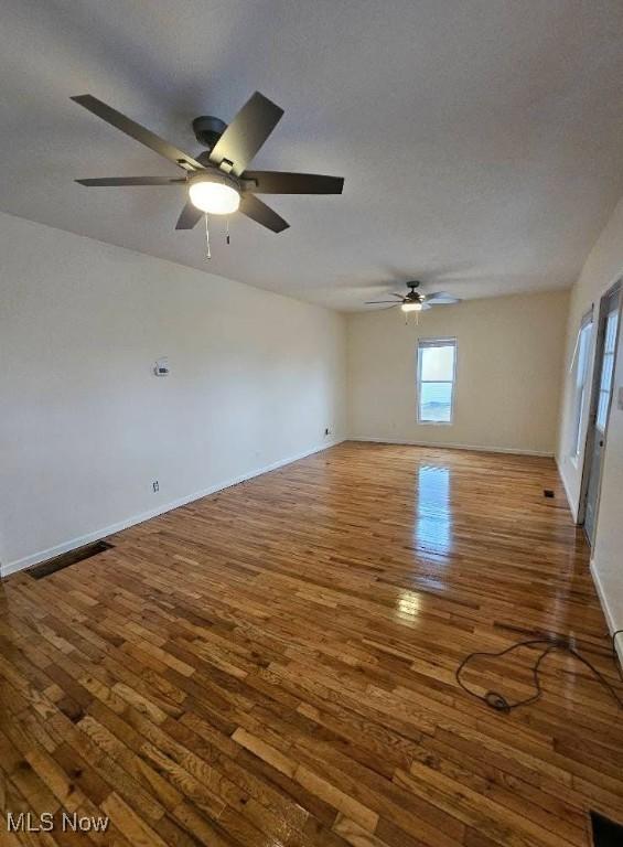 spare room featuring a textured ceiling, wood finished floors, visible vents, and baseboards