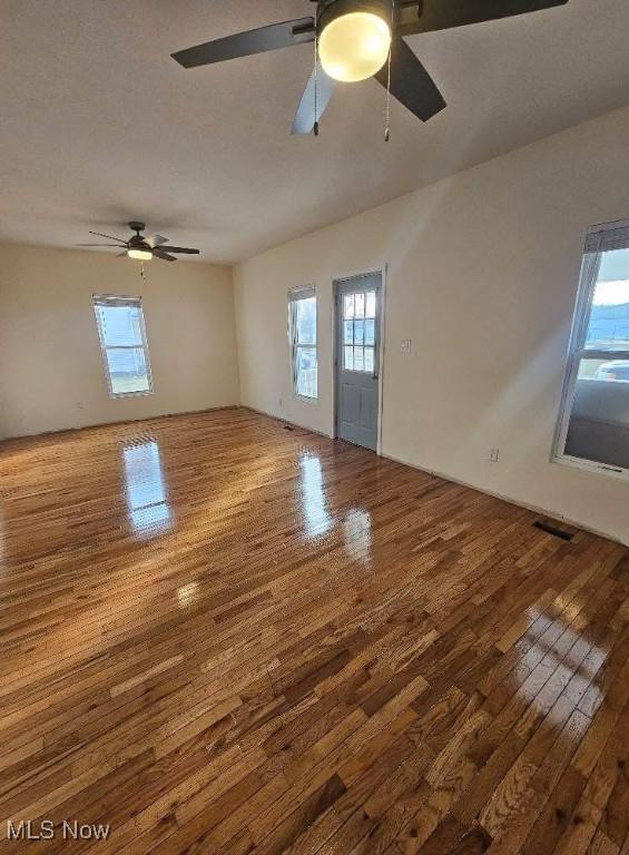 empty room with ceiling fan, a textured ceiling, visible vents, and hardwood / wood-style floors