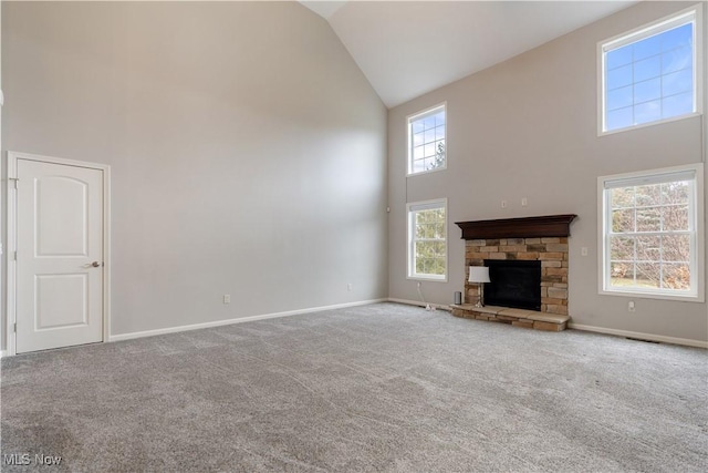 unfurnished living room with high vaulted ceiling, a stone fireplace, carpet flooring, and baseboards