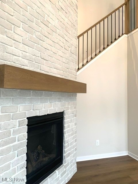 details featuring a brick fireplace, baseboards, and wood finished floors