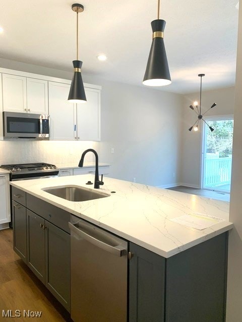 kitchen featuring stainless steel appliances, dark wood-style flooring, a sink, white cabinetry, and tasteful backsplash