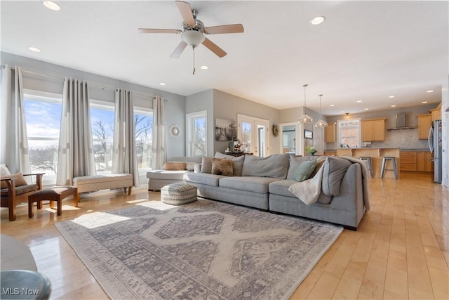 living room with ceiling fan with notable chandelier, recessed lighting, light wood-type flooring, and a healthy amount of sunlight