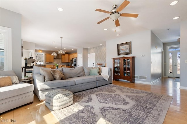 living area featuring light wood-style flooring, visible vents, baseboards, and recessed lighting