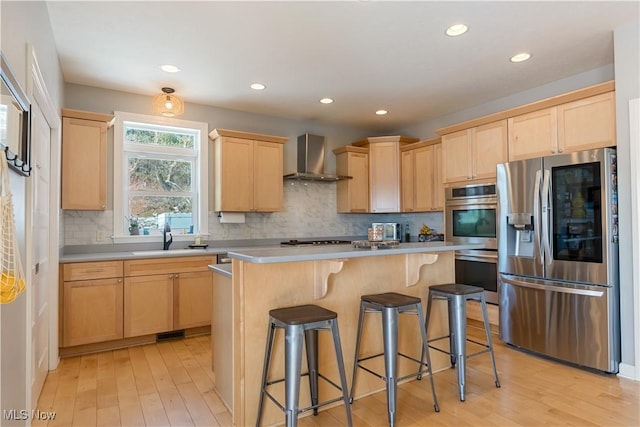 kitchen with wall chimney exhaust hood, a breakfast bar, stainless steel appliances, light countertops, and light brown cabinets