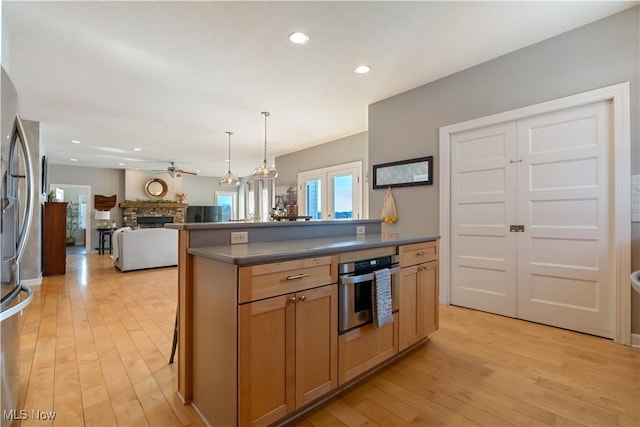 kitchen with dark countertops, light wood-style flooring, a fireplace, and stainless steel appliances