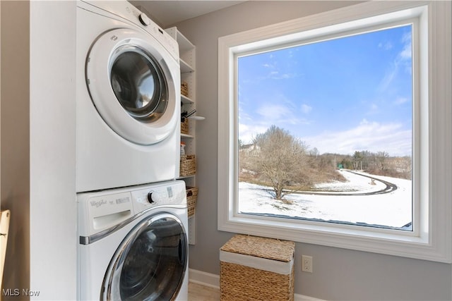 laundry room with stacked washer / dryer, laundry area, and baseboards