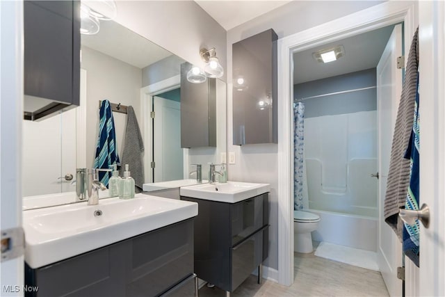 full bathroom featuring two vanities, a sink, shower / bathtub combination with curtain, and toilet