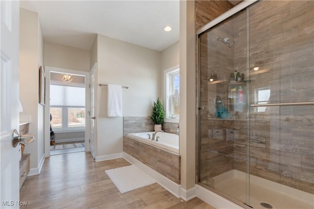 bathroom featuring a bath, a shower stall, baseboards, and wood finished floors