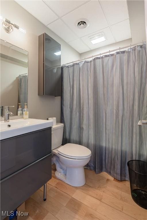 full bath with visible vents, toilet, wood finished floors, vanity, and a paneled ceiling