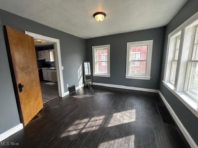 spare room featuring visible vents, baseboards, and wood finished floors