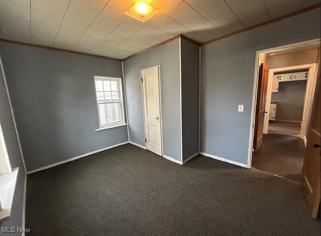 unfurnished bedroom featuring dark carpet, crown molding, and baseboards