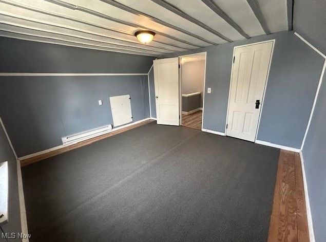 interior space with lofted ceiling, dark carpet, baseboards, and baseboard heating