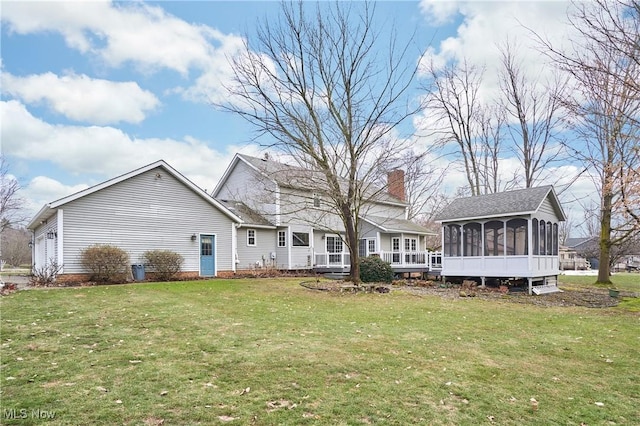 back of property featuring a sunroom, a lawn, a chimney, and an attached garage