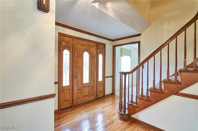 foyer entrance with crown molding, stairway, and hardwood / wood-style floors