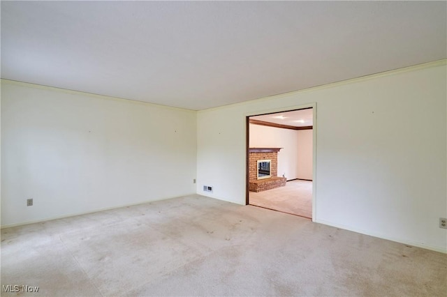 unfurnished room featuring carpet floors, a brick fireplace, visible vents, and crown molding