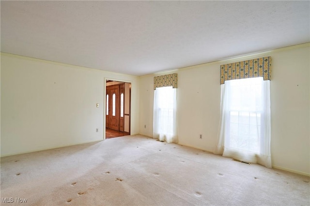 unfurnished room featuring light carpet, baseboards, visible vents, ornamental molding, and a textured ceiling