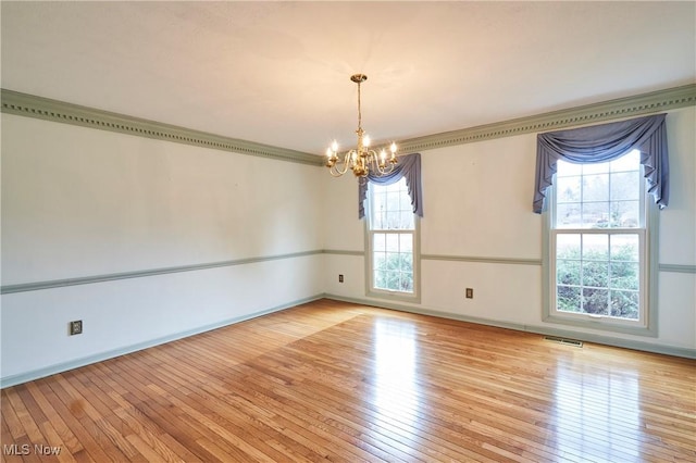 unfurnished room with ornamental molding, wood-type flooring, visible vents, and a notable chandelier