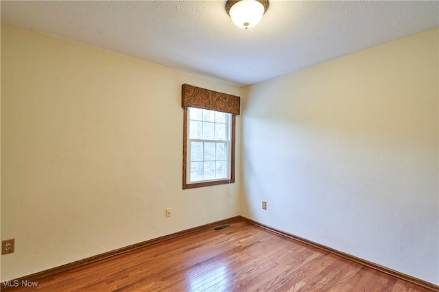 unfurnished room featuring a textured ceiling, visible vents, and wood finished floors