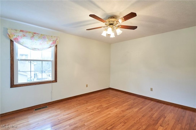 unfurnished room featuring light wood-style floors, baseboards, visible vents, and ceiling fan