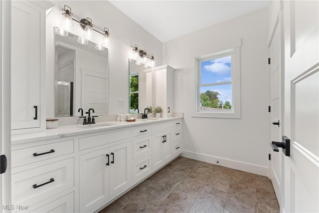 full bath featuring a sink, baseboards, and double vanity