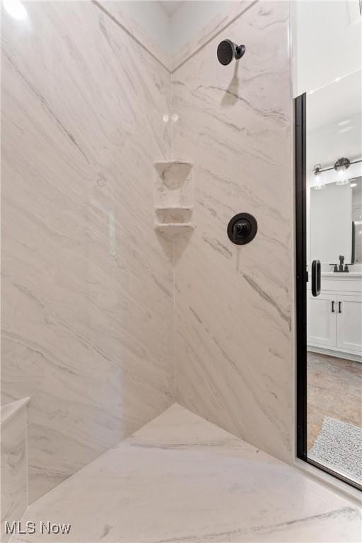 full bathroom with a marble finish shower and vanity