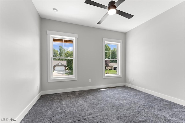 carpeted spare room featuring a healthy amount of sunlight, ceiling fan, and baseboards