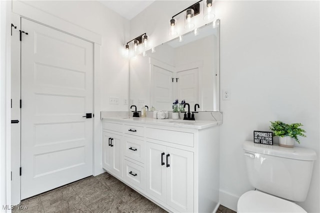 bathroom with double vanity, a sink, and toilet