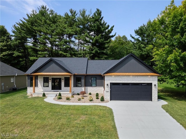 view of front of home featuring driveway, stone siding, a garage, and a front lawn