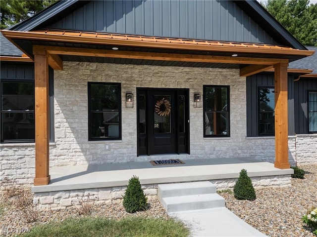 doorway to property with a shingled roof, board and batten siding, and a porch