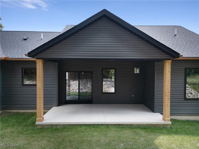 back of property with a shingled roof and a yard