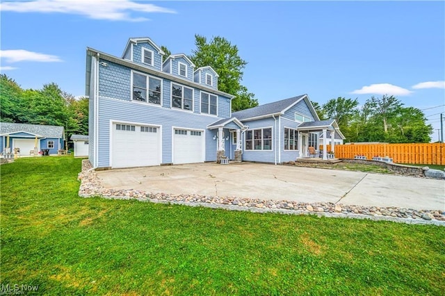 back of property featuring driveway, a lawn, an attached garage, and fence