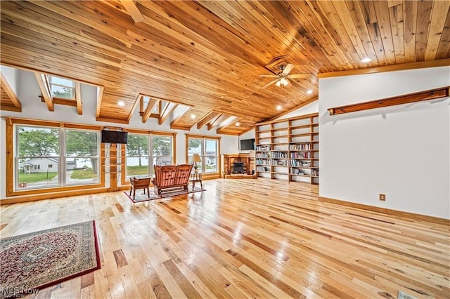 unfurnished living room featuring vaulted ceiling with skylight, wooden ceiling, a fireplace, and hardwood / wood-style floors