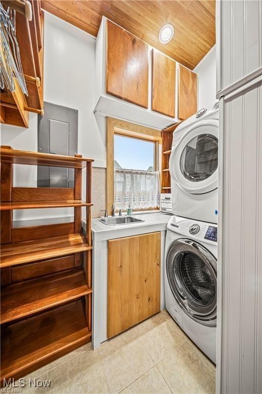 washroom with wooden ceiling, light tile patterned flooring, a sink, stacked washer / drying machine, and cabinet space