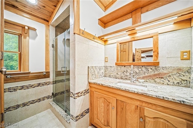 full bathroom featuring tile walls, a shower stall, and vanity