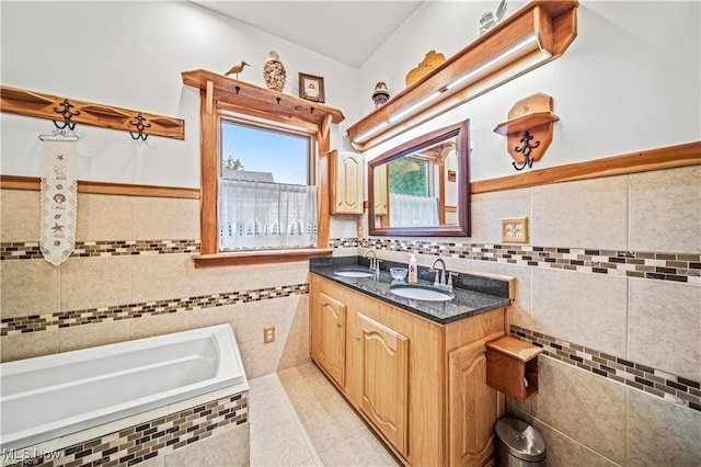 bathroom featuring a bath, tile patterned flooring, a sink, and tile walls