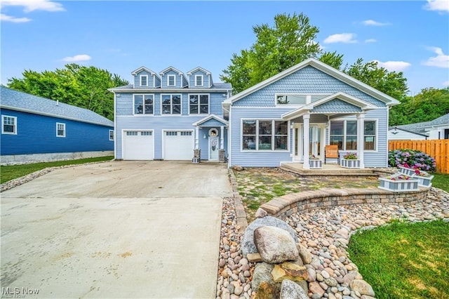 view of front of property with driveway, an attached garage, and fence