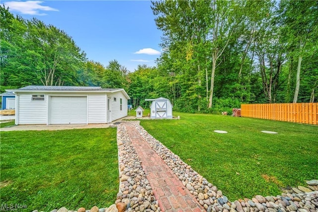 view of yard featuring a garage, fence, and an outdoor structure