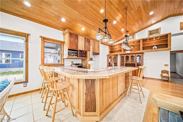 kitchen with lofted ceiling, wooden ceiling, stainless steel microwave, a breakfast bar, and light countertops