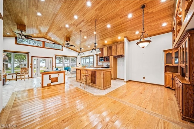 kitchen featuring ceiling fan, light wood-style flooring, wood ceiling, brown cabinetry, and stainless steel microwave