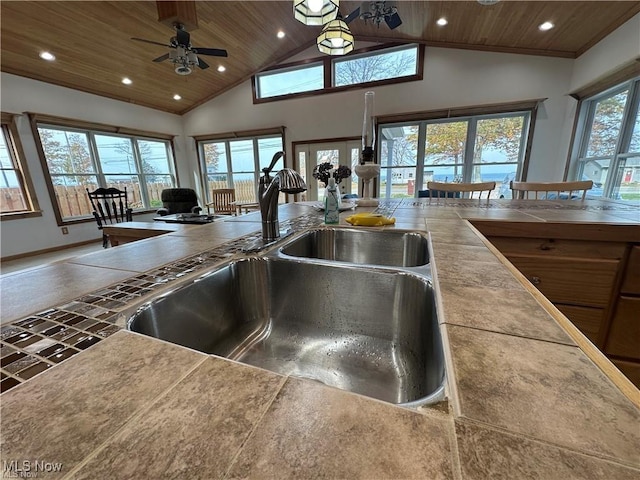 kitchen with high vaulted ceiling, wooden ceiling, a healthy amount of sunlight, and a sink