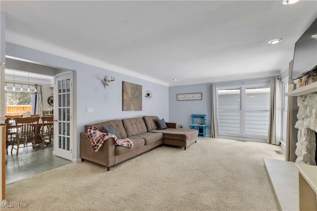 living room featuring a stone fireplace, carpet, and visible vents