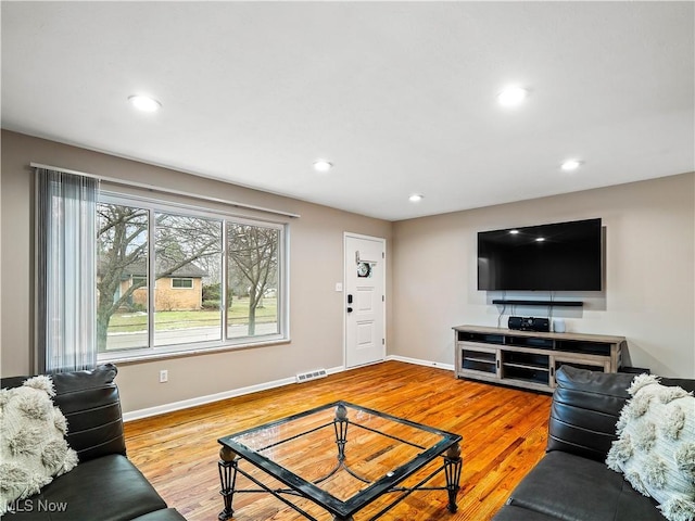 living room with visible vents, baseboards, wood finished floors, and recessed lighting