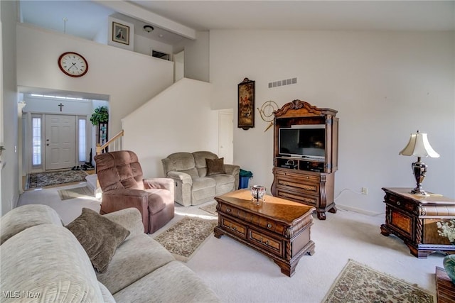 living area featuring high vaulted ceiling, visible vents, and light colored carpet