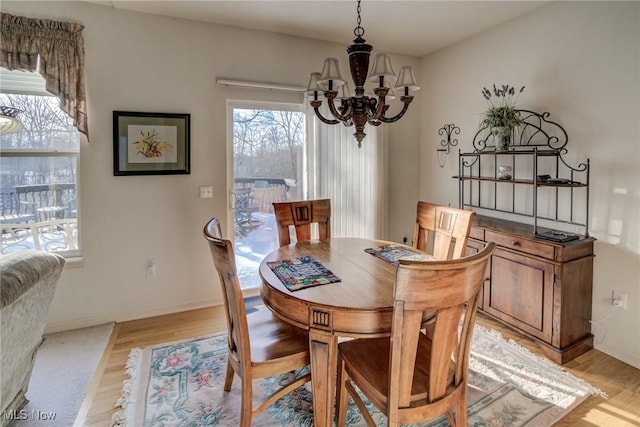 dining space with baseboards, light wood finished floors, and an inviting chandelier