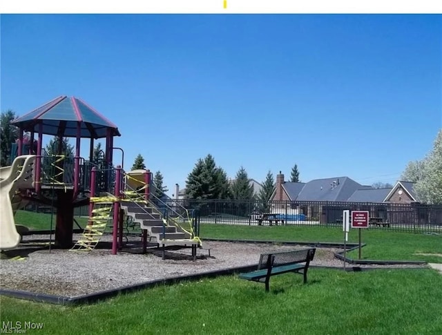 communal playground featuring a yard and fence