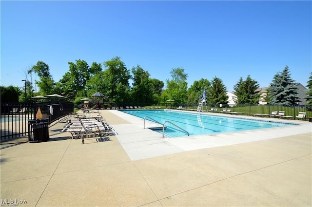 community pool with a patio area and fence