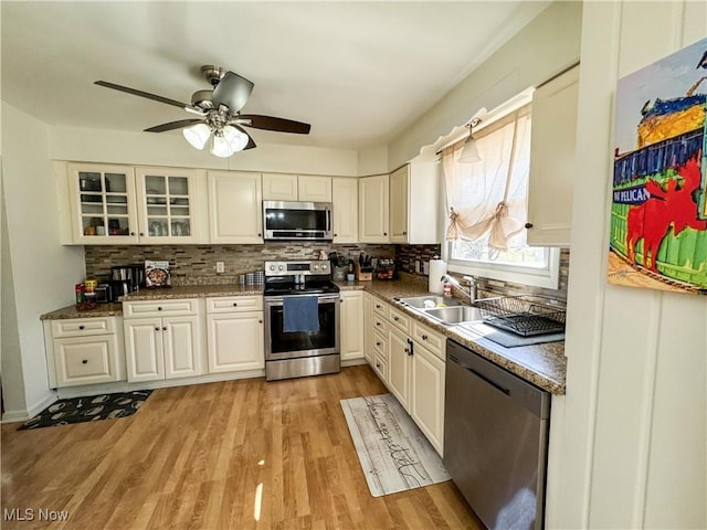 kitchen with tasteful backsplash, appliances with stainless steel finishes, light wood-style floors, white cabinetry, and a sink